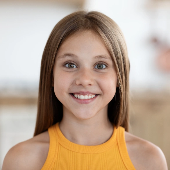 Smiling teenage girl with long brown hair against a light background