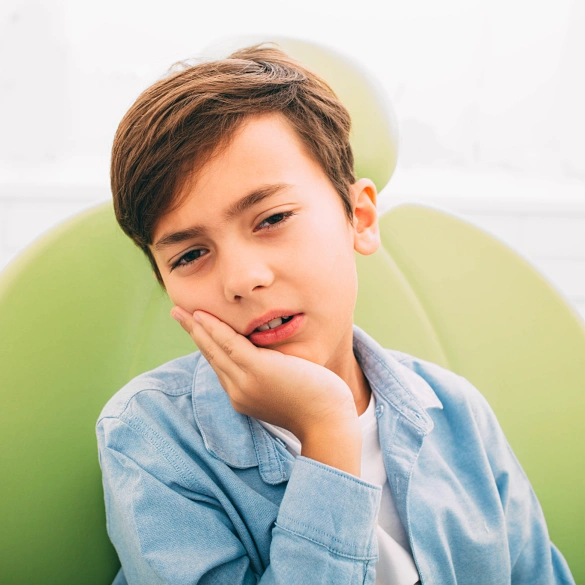 Young boy resting his chin on his hand with a thoughtful expression against a green background