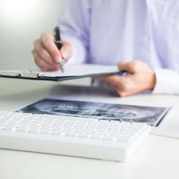 Dental professional reviewing patient paperwork with a pen on a desk