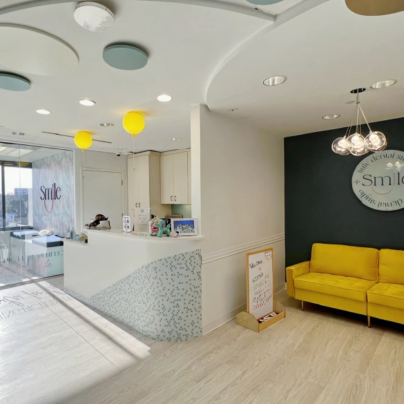 Modern dental office waiting area with yellow seating and a Smile sign above the reception desk