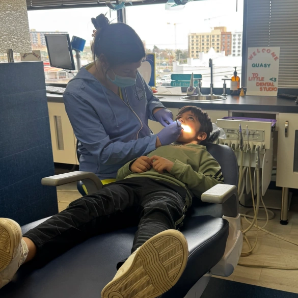 Child patient reclining in a dental chair while a team member assists during an appointment