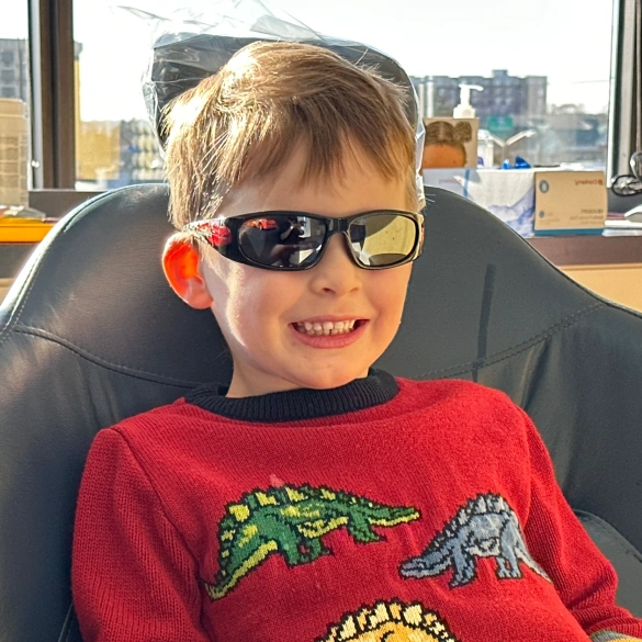 Young boy wearing sunglasses and smiling in a dental chair during a preventive care visit