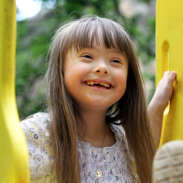 Young girl with Down syndrome smiling warmly outdoors